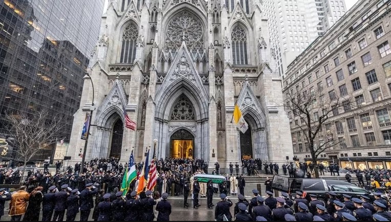 Thousands of mourners pay their respect to a fallen NYPD office.  A significant number of funeral flowers adorned the service.